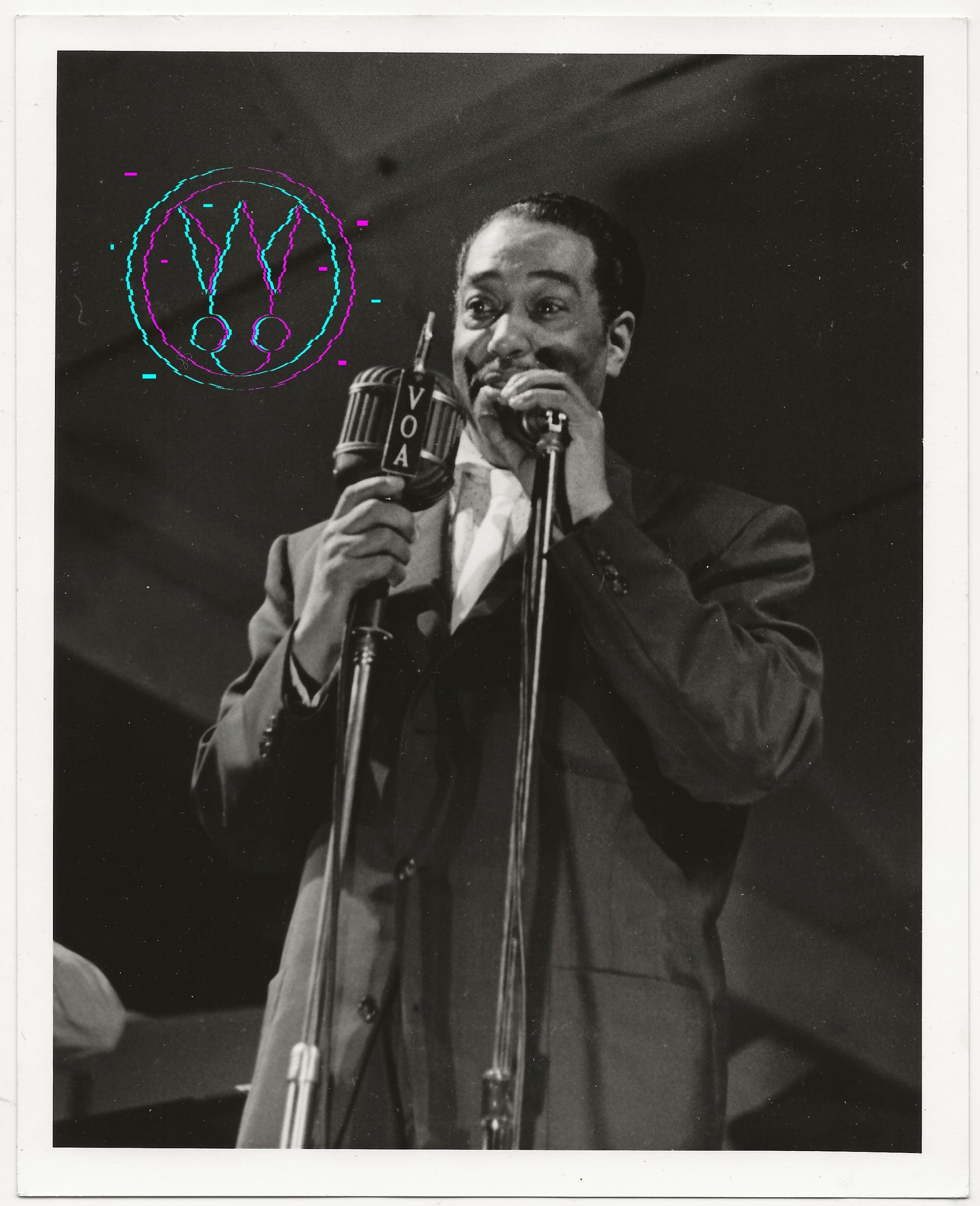 Black and white vintage photograph of a man singing into a microphone on stage, wearing a suit jacket and shirt. The photo has a white border and a colorful circular graphic overlay on the upper left.