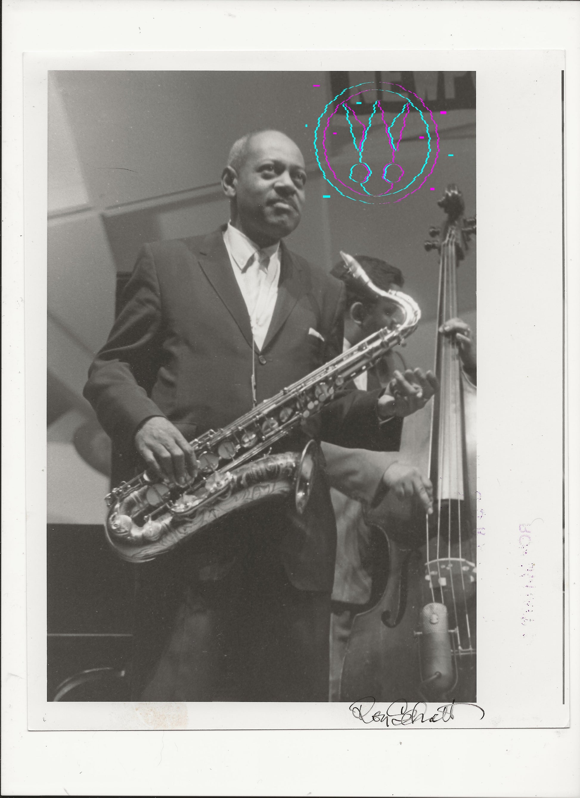 A black and white vintage photograph print of jazz musician Coleman Hawkins playing a tenon saxophone, with a double bass visible in the background. The print features a white border with a handwritten signature at the bottom right and a colorful circular watermark overlay near the top right.